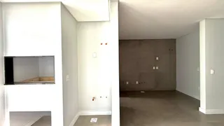 Vista interna de um corredor com paredes brancas e piso de concreto.