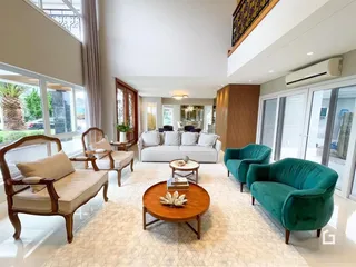 Sala de estar ampla com móveis de madeira e estofados verdes.