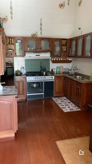 Foto interna de uma cozinha com armários de madeira e piso de madeira.