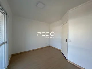 Quarto interno com piso de madeira clara e paredes brancas.