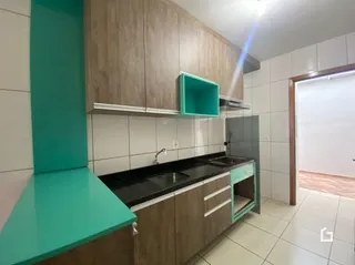 Cozinha com armários de madeira e bancada escura.