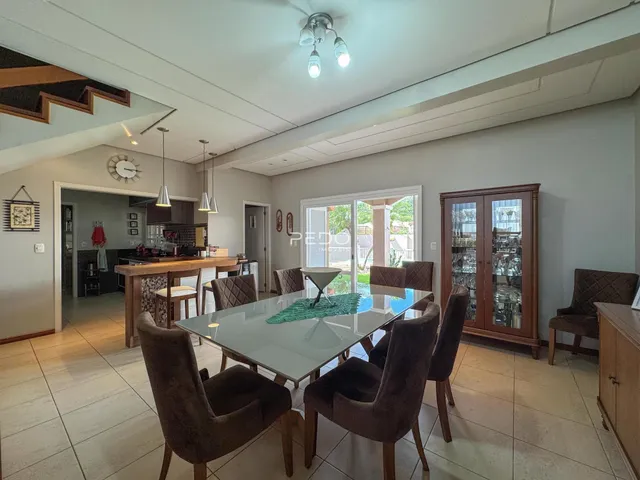 Sala de jantar com mesa de vidro e cadeiras em um ambiente claro.