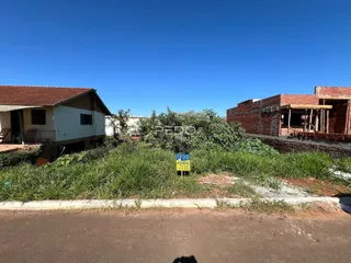 Vista externa de uma propriedade com vegetação alta e duas estruturas adjacentes.