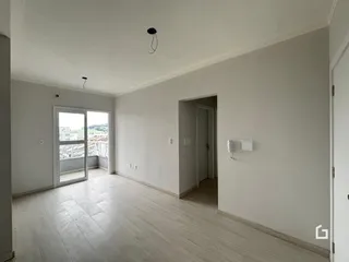 Ambiente interno de uma sala com piso de madeira clara e paredes brancas.