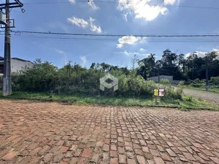Vista da fachada de uma propriedade com área pavimentada e vegetação.