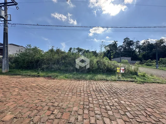 Vista da fachada de uma propriedade com área pavimentada e vegetação.
