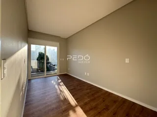 Interior de uma sala com piso de madeira e porta de vidro.