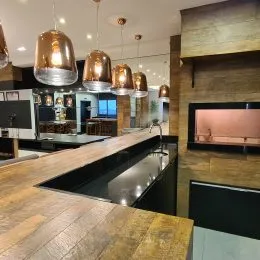 Foto de uma cozinha moderna com bancada escura e iluminação pendente.