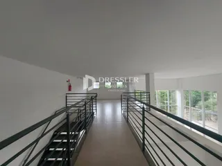 Corredor com escadas e paredes brancas em um imóvel.