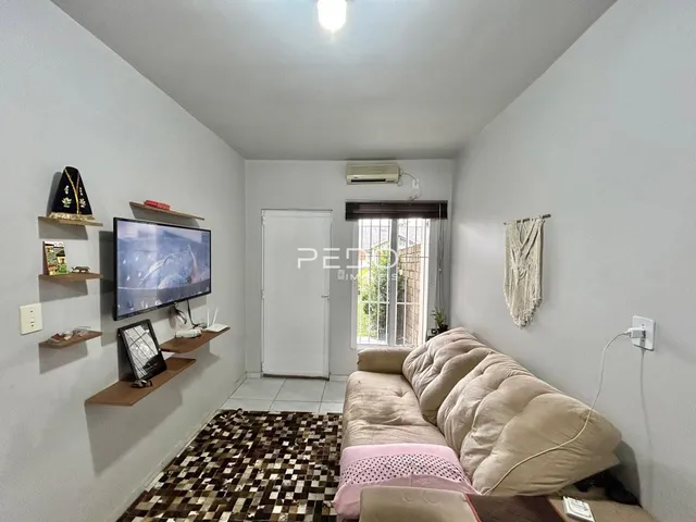 Sala de estar com sofá e televisão em ambiente claro.