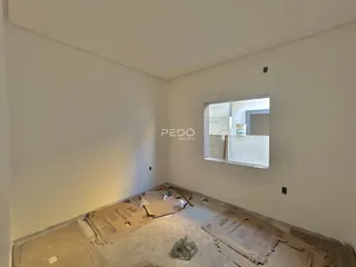 Quarto em reforma com piso exposto e materiais de construção no chão.