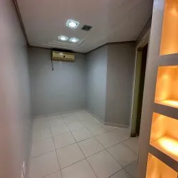 Foto de um corredor interno com piso de cerâmica branca e paredes claras.