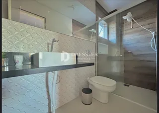Foto de um banheiro com revestimento branco e vidro no interior de uma propriedade.