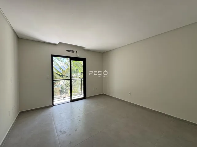 Ambiente interno de uma sala com piso de concreto e porta de vidro.