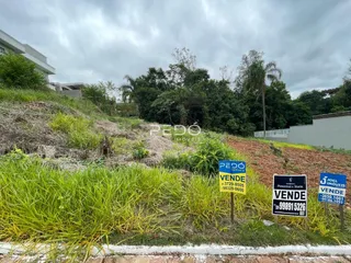Vista externa de uma propriedade com vegetação densa e sinalização no primeiro plano.