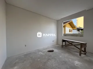 Foto de uma sala de estar vazia com piso de concreto em um imóvel.