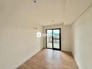 Vista interna de um ambiente com piso de madeira e porta de vidro que dá para o exterior.