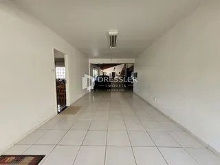 Corredor interno de uma residência com piso de cerâmica clara.
