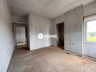 Foto de um cômodo interno em estado de obra com paredes e piso crus.