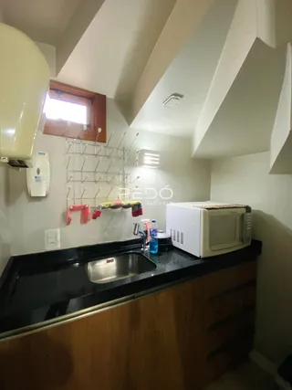 Vista da cozinha com bancada escura e armários de madeira.