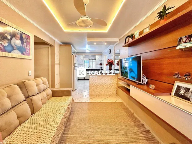 Sala de estar com sofá e televisão em ambiente interno.