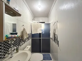 Foto interna de um banheiro com revestimento cerâmico branco.