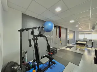 Interior de um espaço com equipamentos de ginástica e piso claro.
