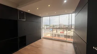 Sala com piso de madeira e grandes janelas de uma residência.