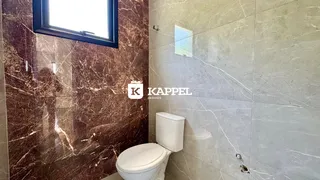 Banheiro com revestimento em mármore e louças brancas.