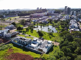 Vista aérea de uma propriedade com área verde e paisagem urbana ao fundo.