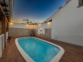 Piscina externa com deck e parede de pedra.
