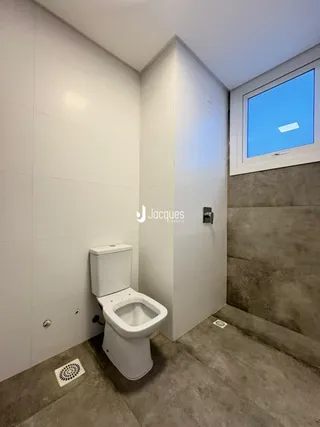 Foto de um banheiro interno com vaso sanitário branco e piso de concreto.