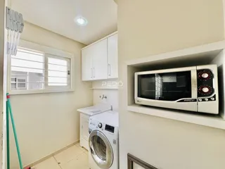 Foto da cozinha com armários brancos e máquina de lavar roupa.