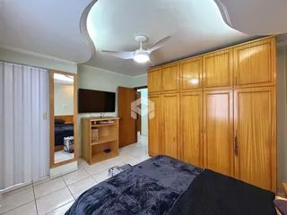 Quarto com armários de madeira e televisão instalada na parede.