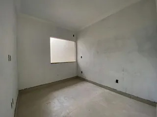 Uma sala ampla e vazia com paredes brancas e piso claro.
