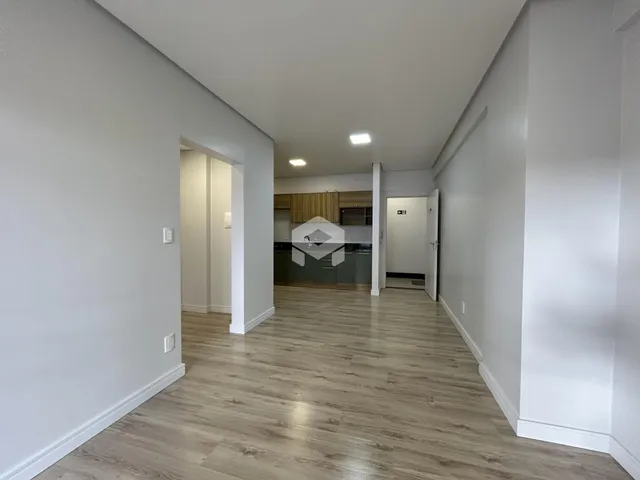 Vista de um corredor interno com piso de madeira clara.