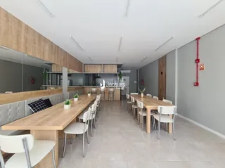 Vista interna de uma sala de jantar com mesa de madeira longa.