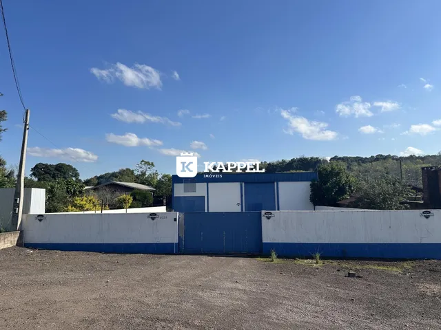 Vista externa de um muro azul e branco com portão de metal em uma propriedade.