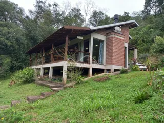 Fachada de uma casa situada em uma colina com vegetação densa.
