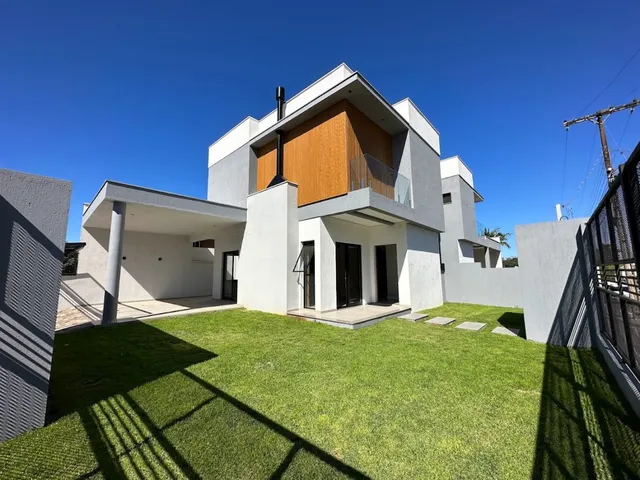 Fachada de uma residência moderna de dois andares com telhado inclinado e jardim gramado.