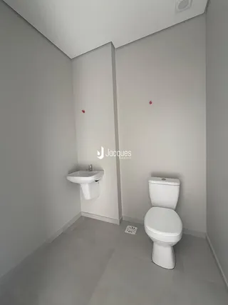 Foto de um banheiro com piso de cerâmica e louças sanitárias brancas.