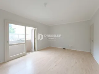 Foto de um ambiente interno de sala com piso claro e porta de vidro.