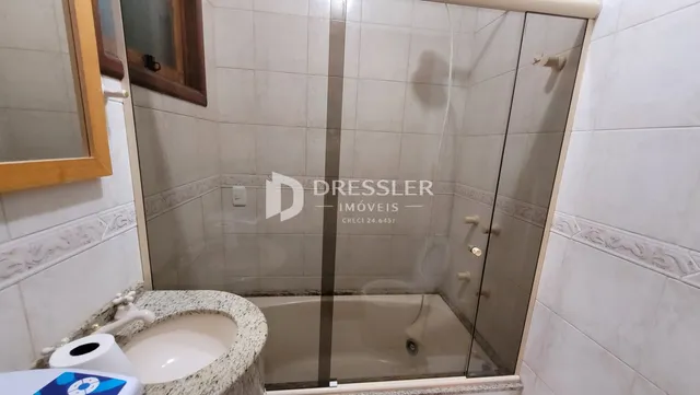 Foto de um banheiro com banheira de vidro e revestimento cerâmico.