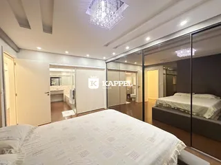 Quarto espaçoso com cama grande e iluminação de lustre de cristal.