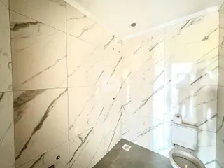 Parede revestida com azulejos marmorizados em um banheiro.
