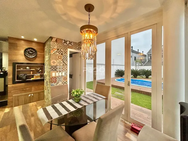 Sala de jantar com vista para o jardim e piscina através de portas de vidro.