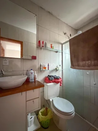 Foto interna de um banheiro com revestimento cerâmico e bancada de madeira.