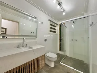 Imagem de um banheiro moderno com box de vidro e bancada de mármore.