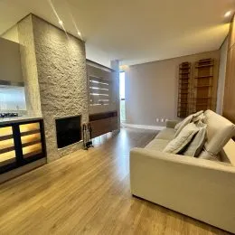 Sala de estar com piso de madeira clara e um sofá branco.