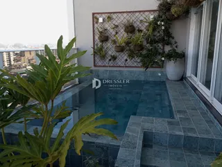 Vista de uma área externa com piscina e vegetação.